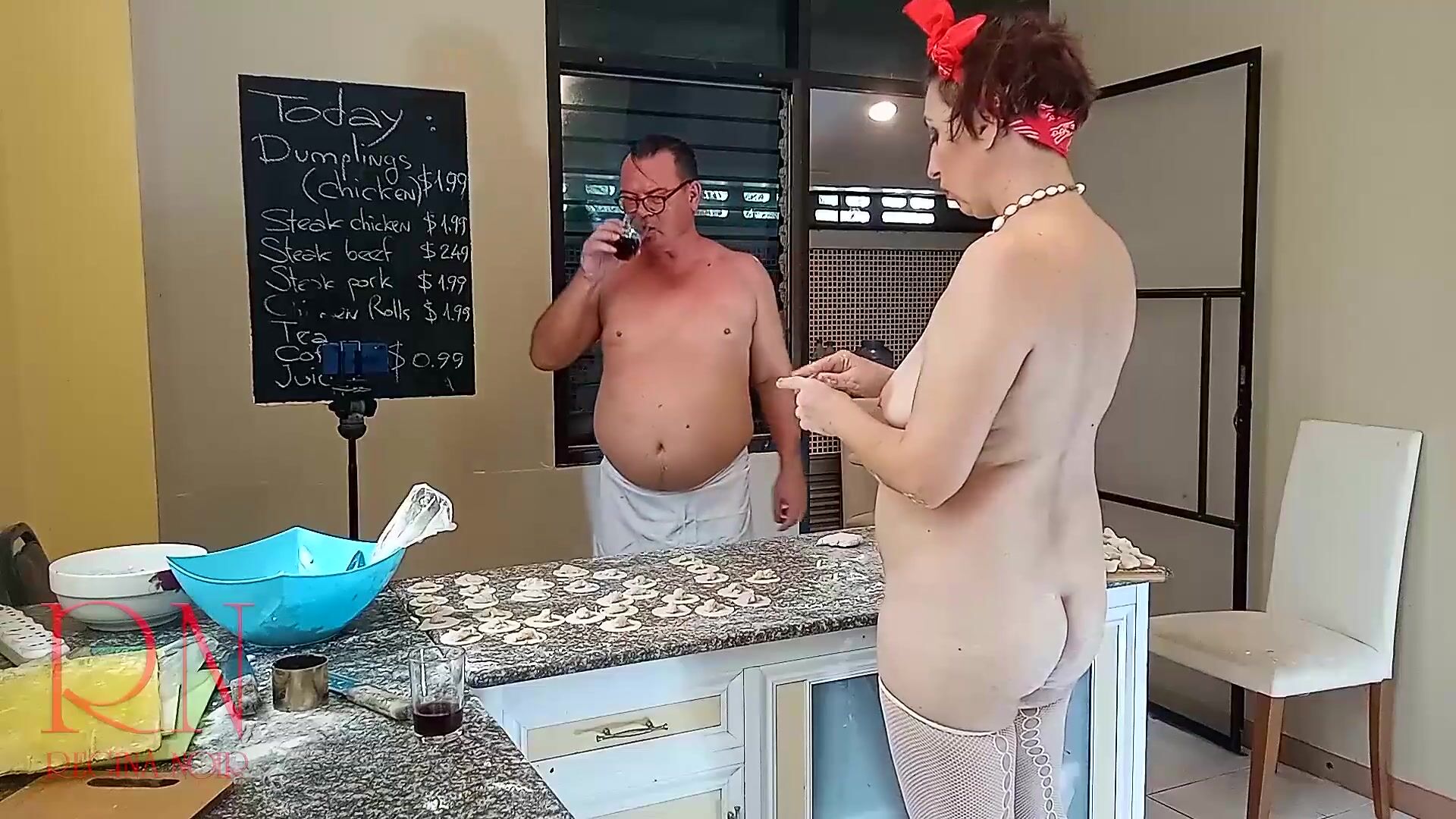 A naked housewife is preparing dinner in the kitchen