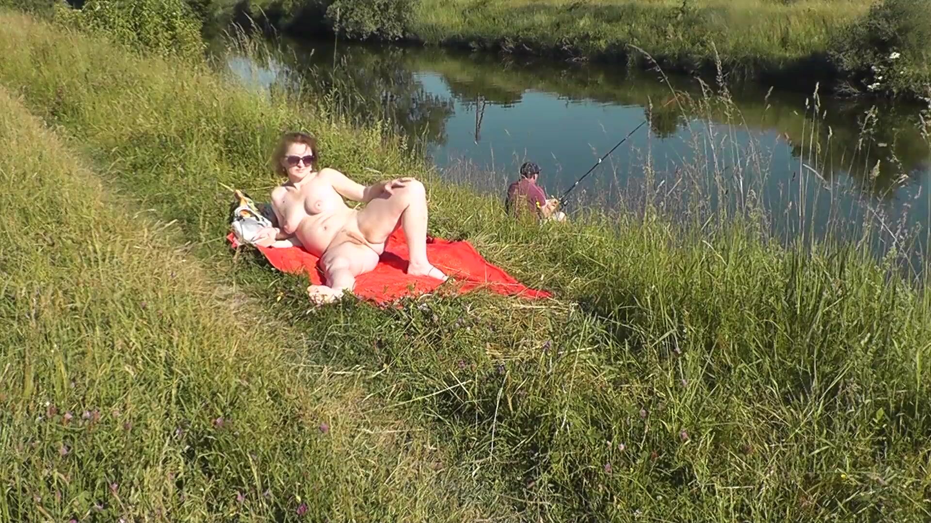 MILF sexy Frina on river bank undressed and sunbathes naked. Random man fisherman watching for her, and in the end decided to join naked woman. Wild beach. Nudist beach