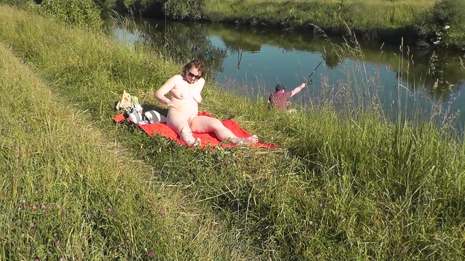 MILF sexy Frina on river bank undressed and sunbathes naked. Random man fisherman watching for her, and in the end decided to join naked woman. Wild beach. Nudist beach